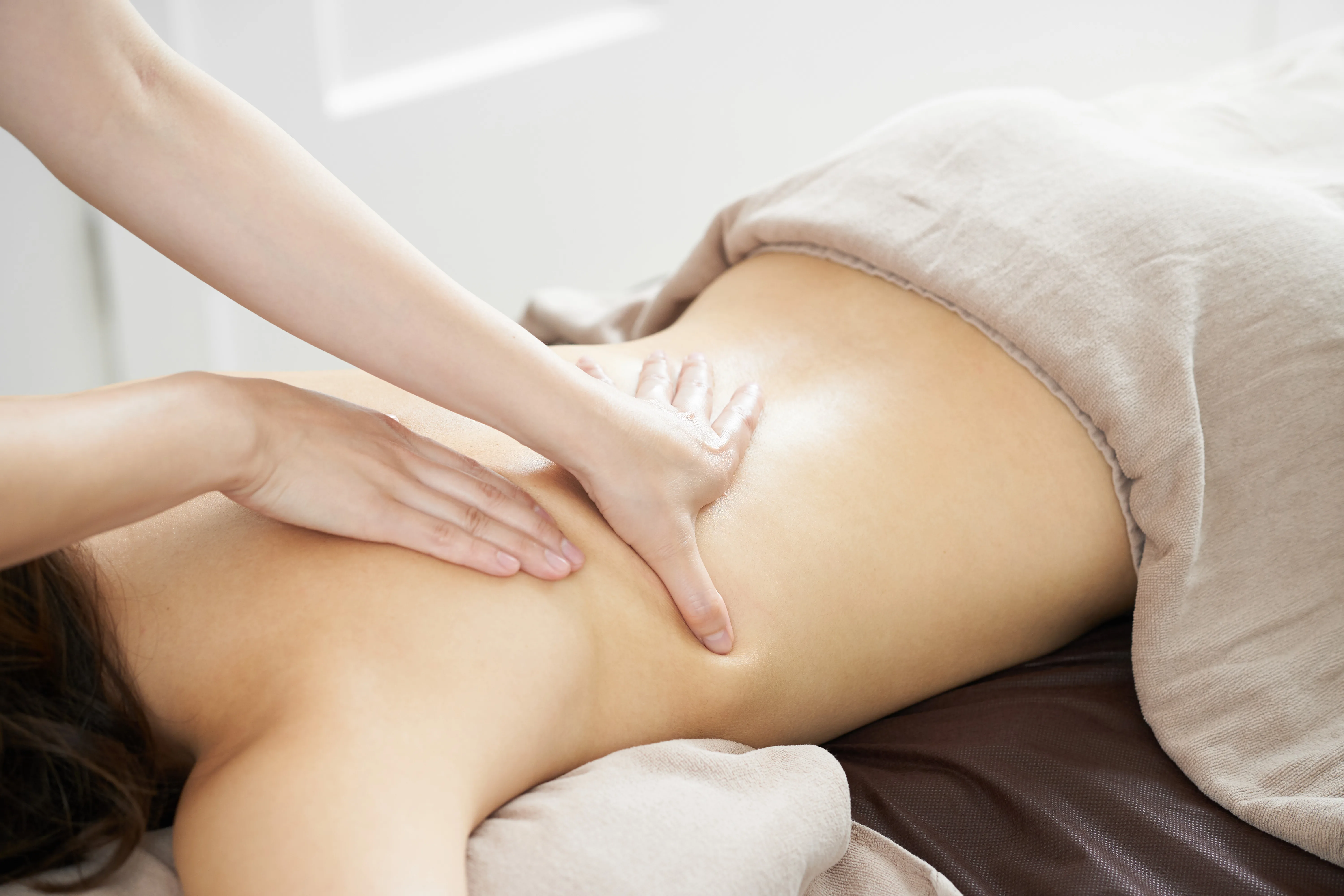 Woman receiving back massage at a bright beauty salon