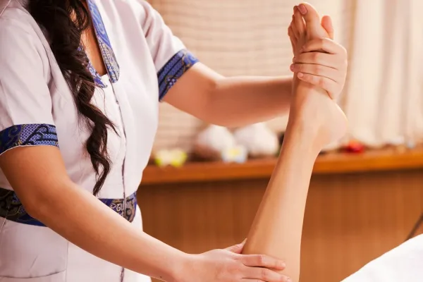 Legs massage. Confident Thai massage therapist massaging beautiful female leg