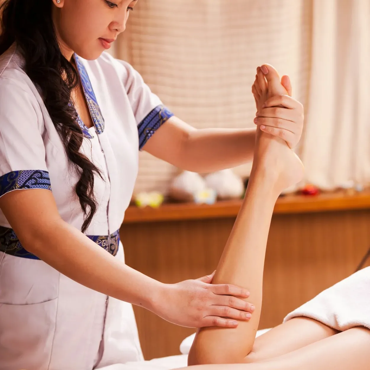 Legs massage. Confident Thai massage therapist massaging beautiful female leg