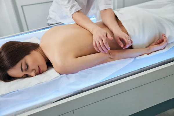 Massage therapist leaning on woman back with two arms