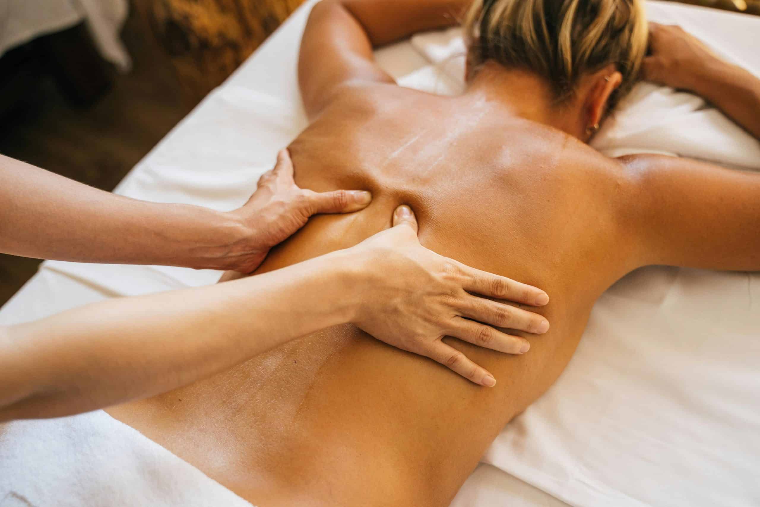 A person massaging a client s bare back