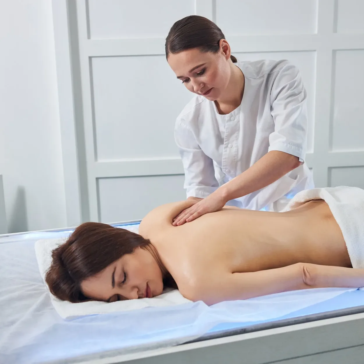 Masseuse kneading the shoulder skin with her palm Masseuse kneading the shoulder skin with her palm